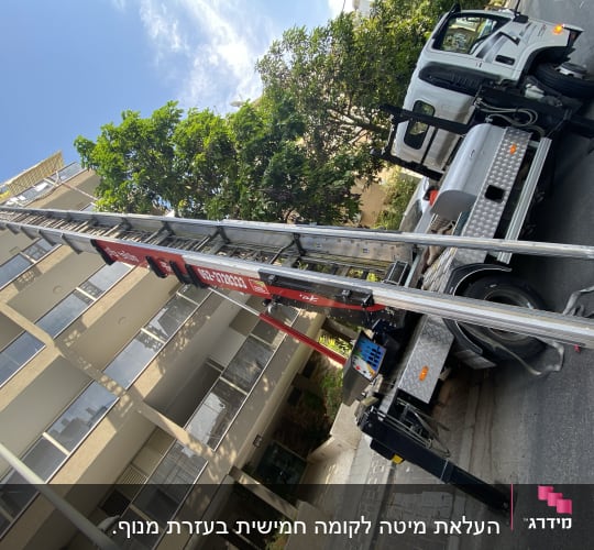 מנוף על משאית ליד בניין גבוה